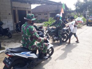 Dengan Mengendarai Sepeda Motor , Babinsa Bantu Warga Pasang Umbul-Umbul .
